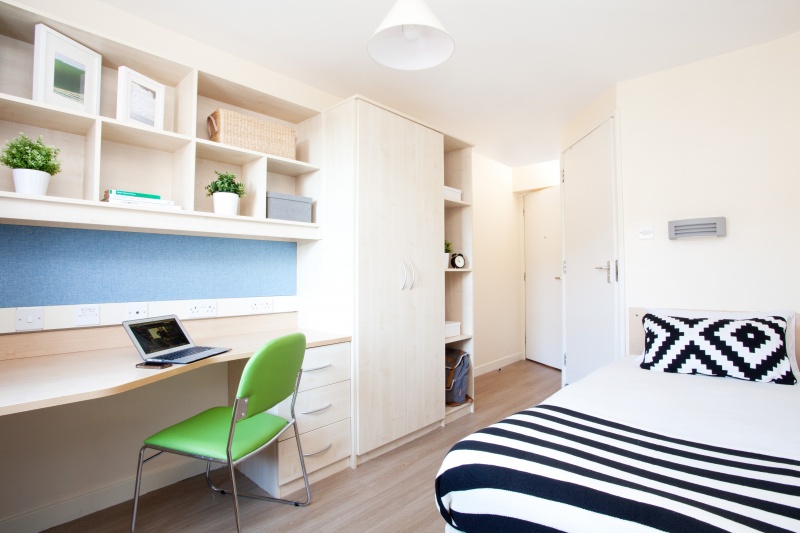 student bedroom with bed, desk, and storage at The Old Fire Station