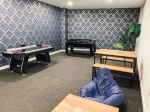 The games room with sofas, pool table, foosball and armchairs in The Paper Works residence