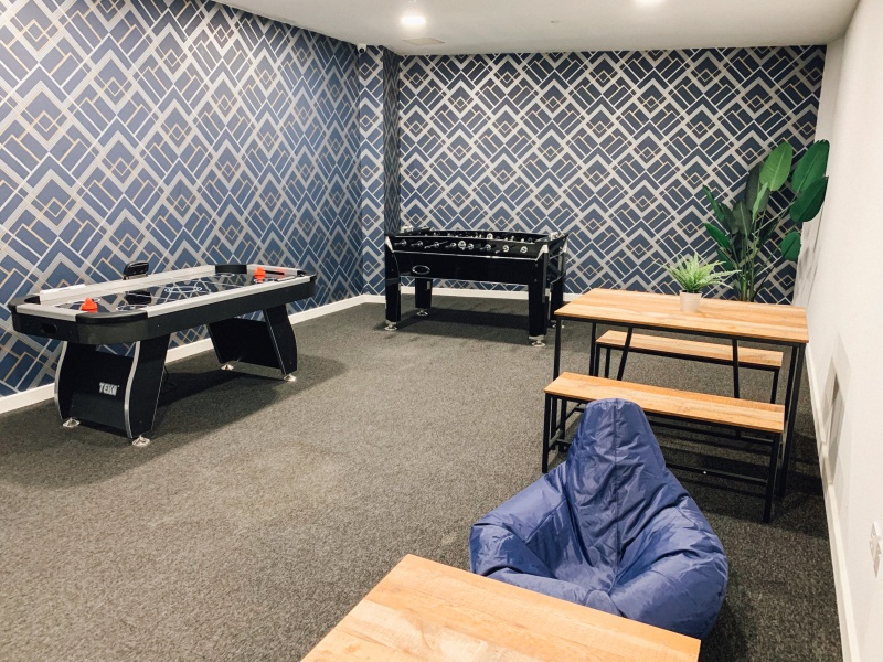 The games room with sofas, pool table, foosball and armchairs in The Paper Works residence