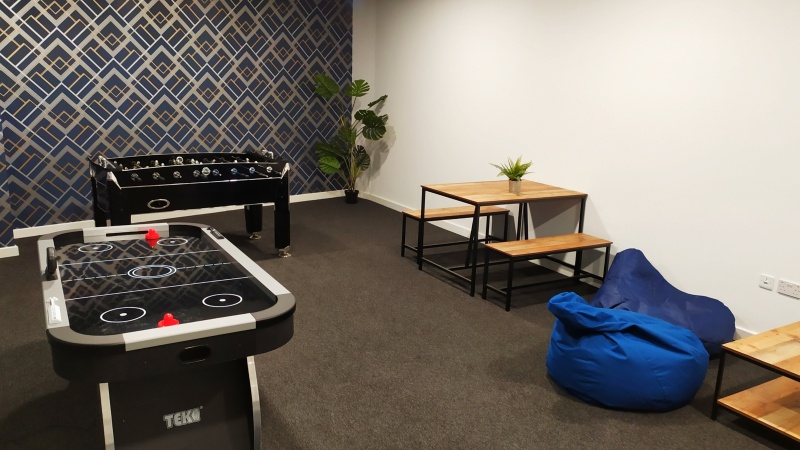 The games room with sofas, pool table, foosball and armchairs in The Paper Works residence