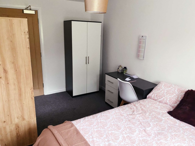 Comfortable student bedroom at Park Village, with a double bed, desk, and wardrobe