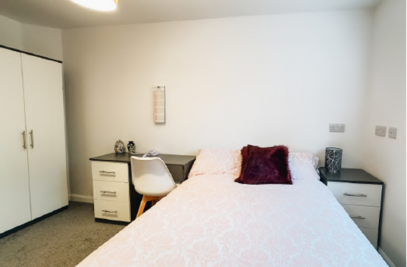 Comfortable student bedroom at Park Village, with a double bed, desk, and wardrobe