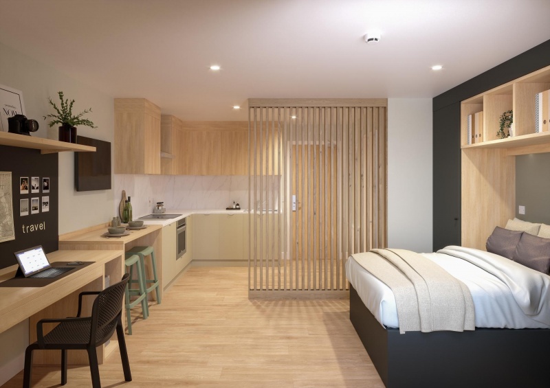 A modern student studio room with a kitchen, desk, and bed, separated by a wooden partition