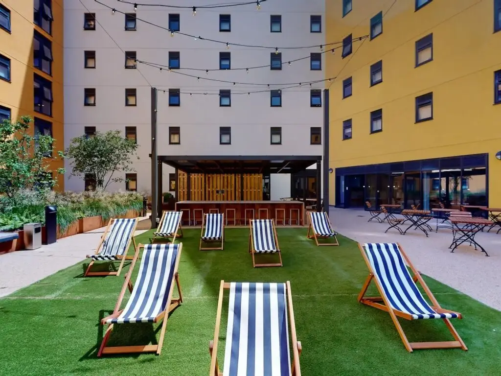 Courtyard with striped deckchairs on artificial grass at Seren student accommodation, Swansea.