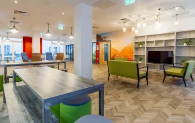 Modern dining area at Plymouth Cross House with white tables and green chairs.