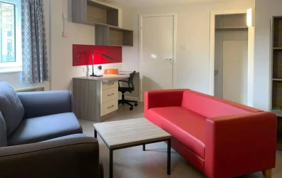 Spacious living area with red couch and study desk at Hamwic Hall, Southampton