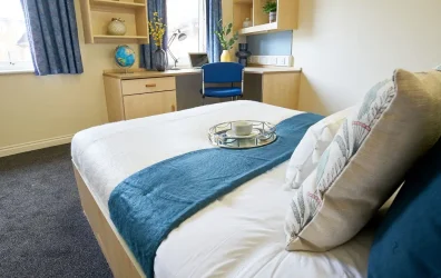 View of student room, bed, study table, window in Trinity Student Village