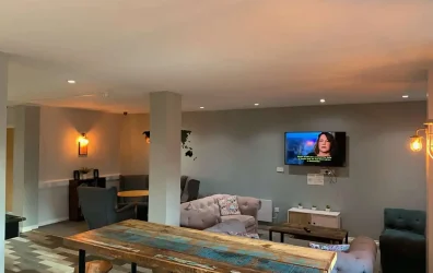 A contemporary communal dining room with stylish furniture and kitchen facilities atThe Warehouse Ap
